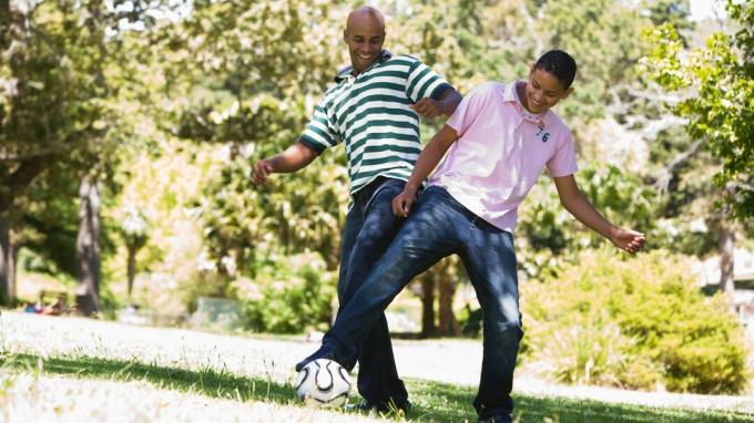 Un tată care își parintează adolescentul jucând un joc distractiv de fotbal